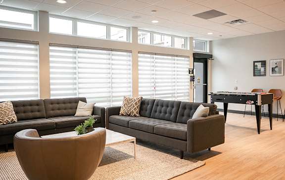 A modern living room with a black couch, a wooden coffee table, and a piano.