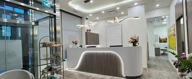 A reception area with a white reception desk and a grey carpet.