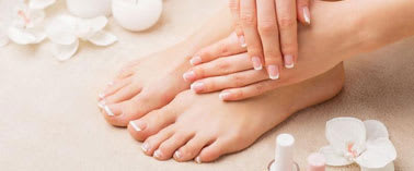 A woman's feet being massaged with white flowers and candles around.