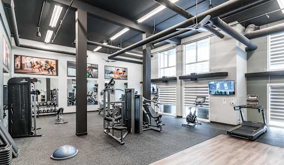 A gym with a variety of equipment including treadmills, weights, and exercise machines.