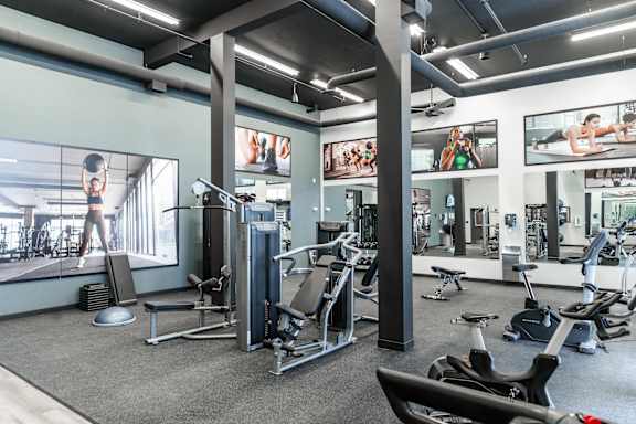 A gym with a variety of equipment including treadmills, weights, and exercise machines.