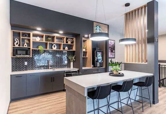 A modern kitchen with a large island and bar stools.at Skyway Apartments, Calgary, AB T3B 5V6