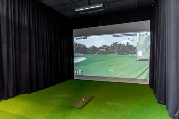 A golf simulator room with a screen showing a golf course.