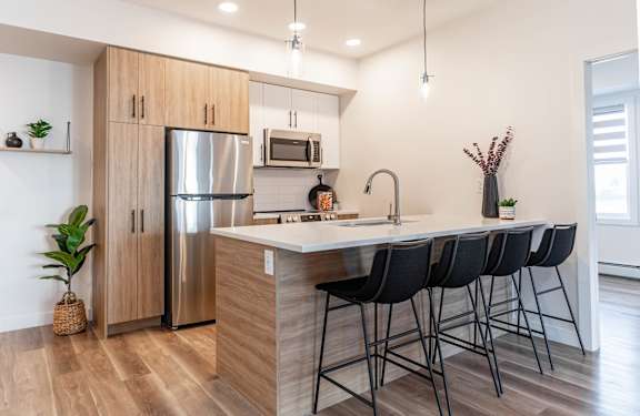 A kitchen with a refrigerator, microwave, and sink.at Vibe Apartments at Arbour Lake, Calgary, T3G 4J2