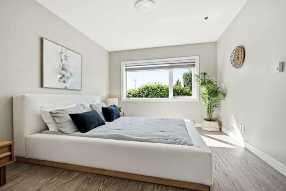 A bedroom with a large bed and a window overlooking greenery.