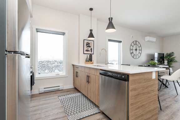 A modern kitchen with a large window and a stainless steel dishwasher.at Latitude 49 Townhomes, Winnipeg