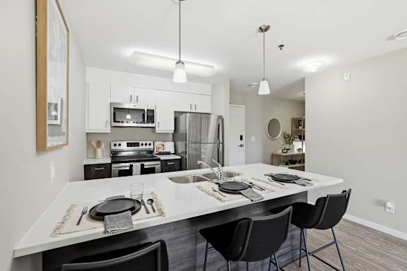 A modern kitchen with a dining table set for two.