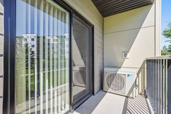 A modern house with a sliding glass door and a wall-mounted air conditioner unit.