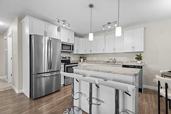 A kitchen with white cabinets and a marble countertop.