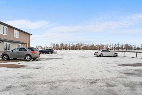 A parking lot with three cars and a building in the background.