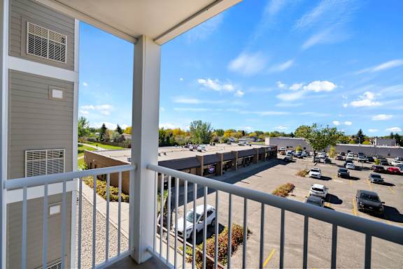 A balcony overlooks a parking lot and buildings.