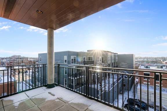 A balcony with a black railing and a concrete pillar.at Raymond Block, Edmonton, T6E 3R7