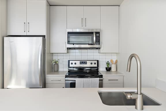 A modern kitchen with a stainless steel refrigerator, microwave, and oven.at Raymond Block, Edmonton Alberta T6E 3R7