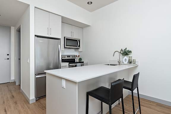 A kitchen with a white countertop and black chairs.at Raymond Block, Edmonton Alberta T6E 3R7