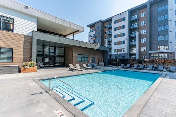 A swimming pool in front of a building with lounge chairs around it. at Skyway Apartments, Alberta, T3B 5V6