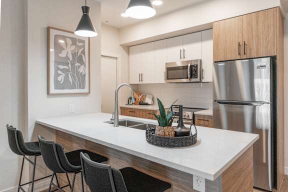 A modern kitchen with a white countertop and stainless steel appliances.