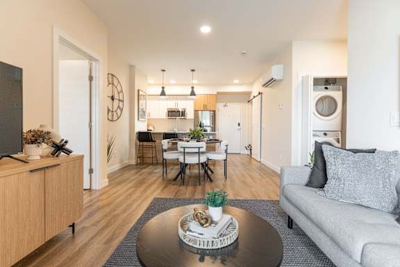 A modern living room with a grey sofa and a wooden cabinet. at Vista Apartments at Edgemont, Edmonton, AB