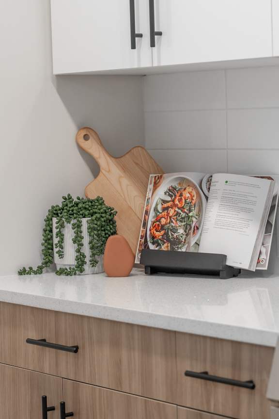 A cutting board, a knife, and a magazine are on a kitchen counter.