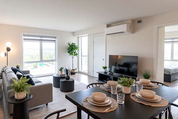 A modern living room with a grey couch, a black coffee table, and a flat screen TV at Skyway Apartments, Alberta, T3B 5V6