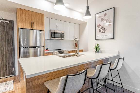 A kitchen with a white countertop and wooden cabinets.at The Artisan at Rangeview, Calgary, Alberta