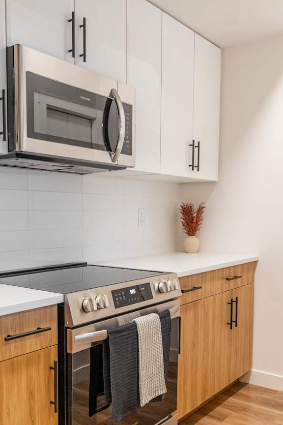 A modern kitchen with a stainless steel microwave above the stove.at The Artisan at Rangeview, Calgary, Alberta