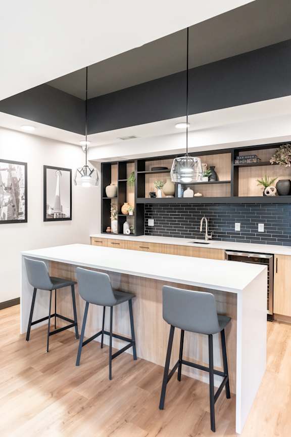 A kitchen with a white counter and two grey bar stools.