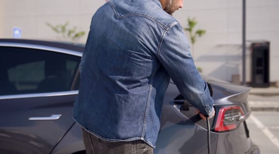 a man refueling his car in a parking lot