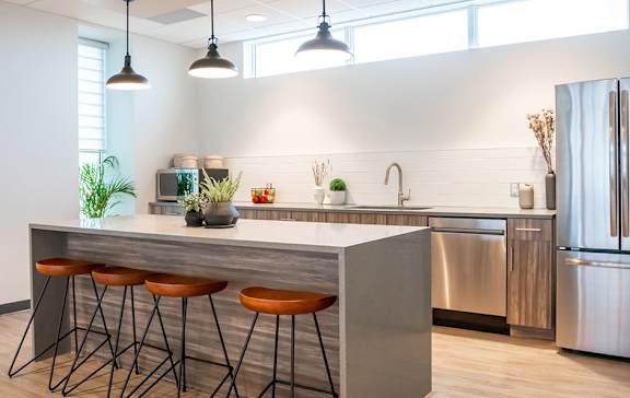 A modern kitchen with a bar stool and a refrigerator.