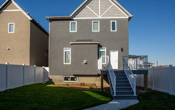 A modern house with a white fence and a staircase leading to the entrance.