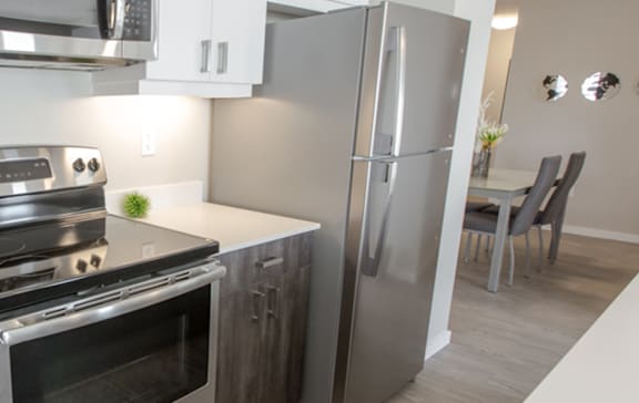 A black refrigerator is in a kitchen with wooden cabinets.
