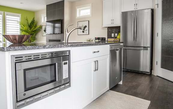 A modern kitchen with a stainless steel oven and white cabinets.