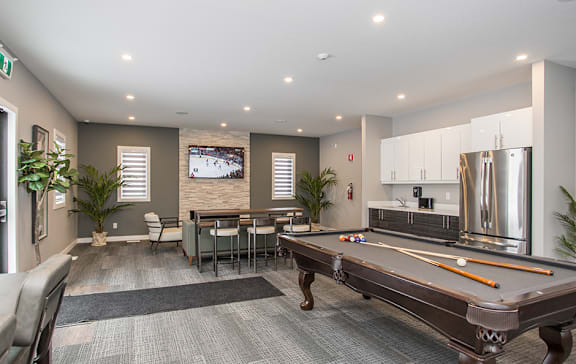 A pool table is in the middle of a room with a dining table and chairs.