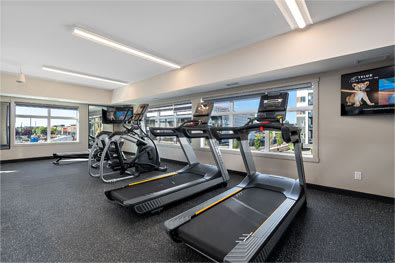 A treadmill and a stationary bike are in a gym.