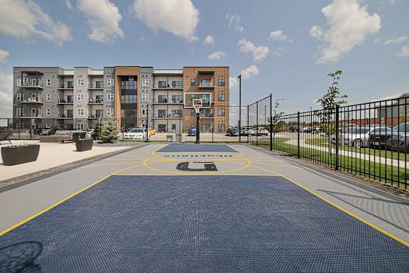 A basketball court in front of apartment buildings.