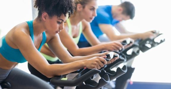 Three people are working out on exercise bikes in a gym.at Vista Apartments at Edgemont, Edmonton, AB