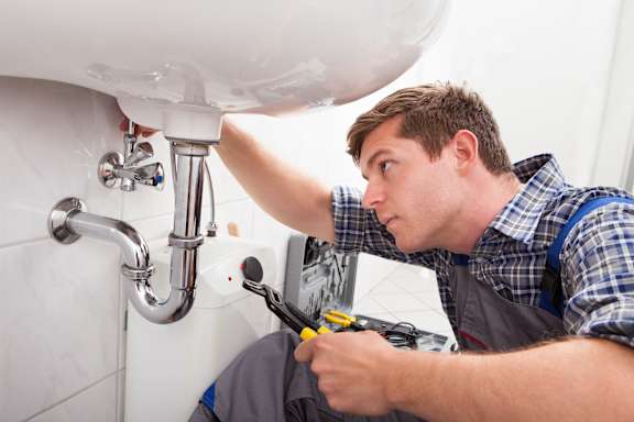 A plumber is fixing a sink at The Artisan at Rangeview, Calgary