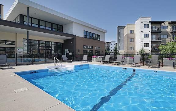 A swimming pool in front of a building with a sign that reads "Park 1.3 M".