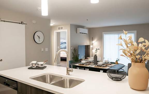 A modern kitchen with a white countertop and stainless steel sink.