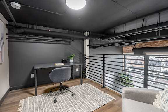 A modern home office with a desk, chair, and a window with blinds.at Raymond Block, Edmonton, AB T6E 3R7