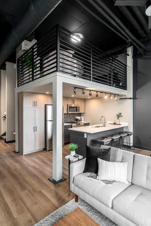 A modern kitchen with a white couch and wooden floors.at Raymond Block, Edmonton, AB T6E 3R7