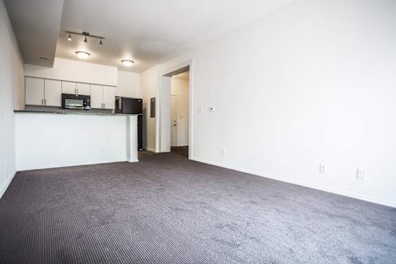 A large empty room with a carpeted floor and white walls.