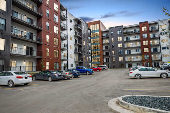 A parking lot with cars and apartment buildings in the background.