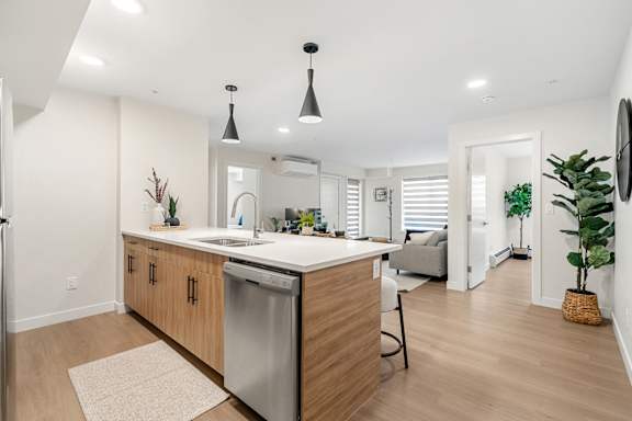 A modern kitchen with wooden cabinets and a stainless steel dishwasher. at Skyway Apartments, Alberta, T3B 5V6