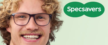 A man with curly hair and glasses is smiling.