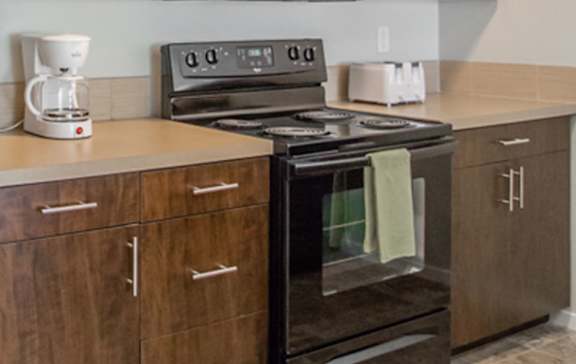 A black stove top oven with four burners and a digital display is on a kitchen counter.