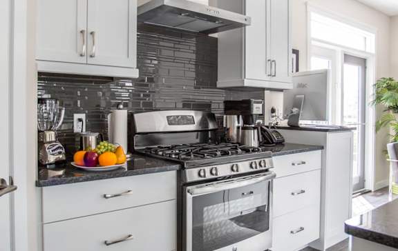 A modern kitchen with a stove top oven and white cabinets.
