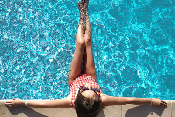 A woman in a red and white swimsuit is floating in a pool.