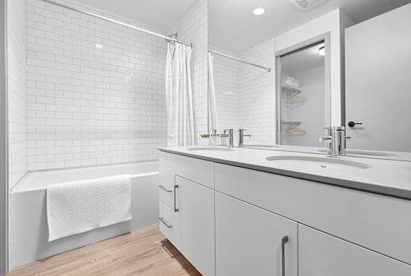A white bathroom with a white tub, sink, and shower.at Raymond Block, Edmonton