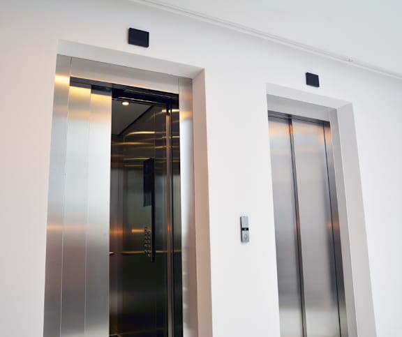 Modern elevator lobby with stainless steel doors at Mac and Mullen Apartments, Edmonton, AB
