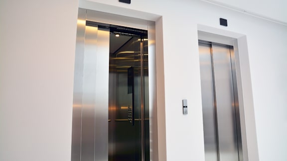 A modern stainless steel elevator in a white room.
